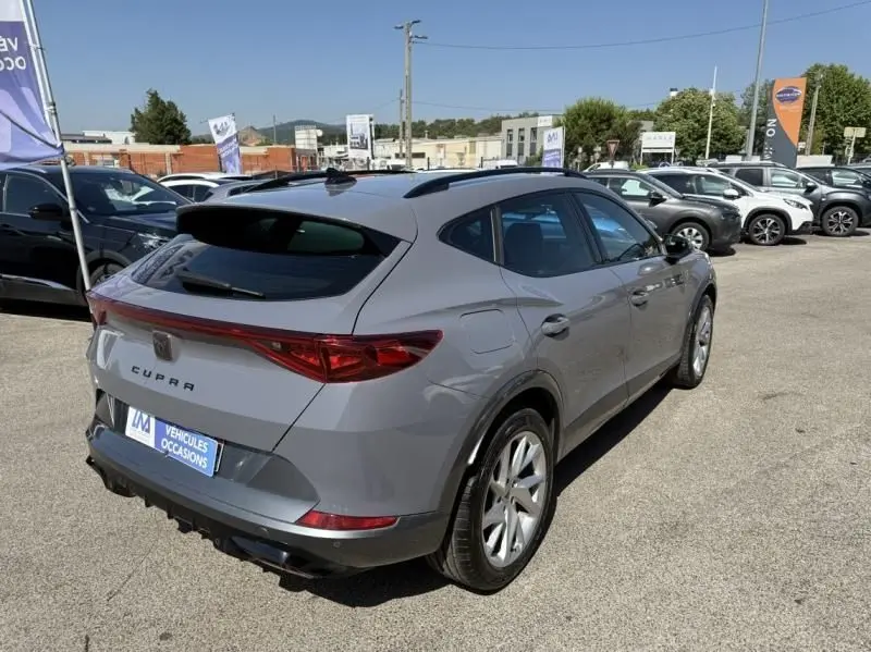 Vue 3/4 arrière droite d'un CUPRA Formentor gris 2023 hybride essence, avec jantes argentées et toit noir.