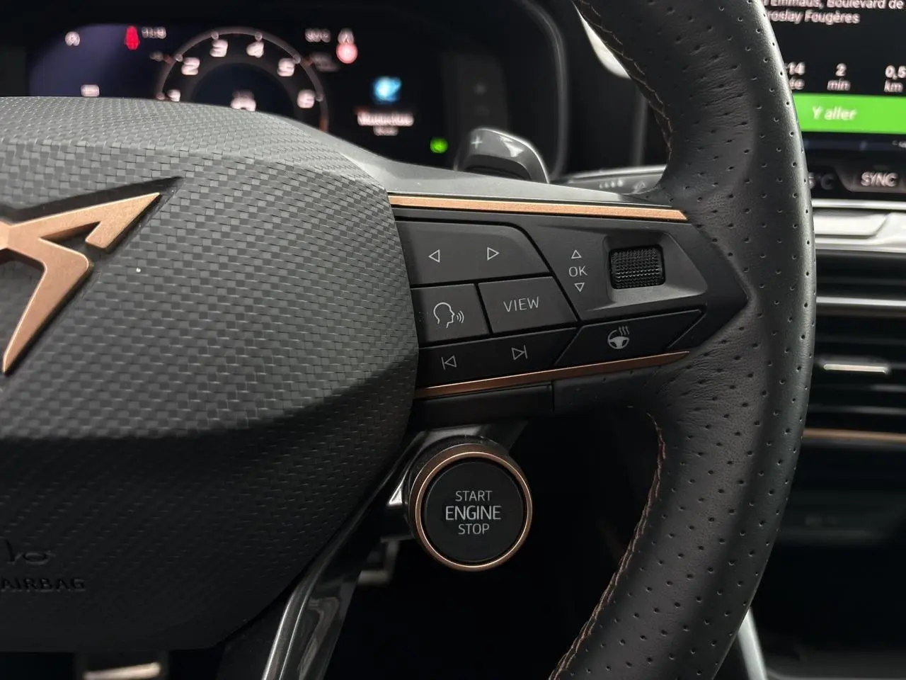Gros plan sur le volant cuir perforé noir avec logo CUPRA cuivré et bouton start/stop du Leon ST Gris Graphene 2025.