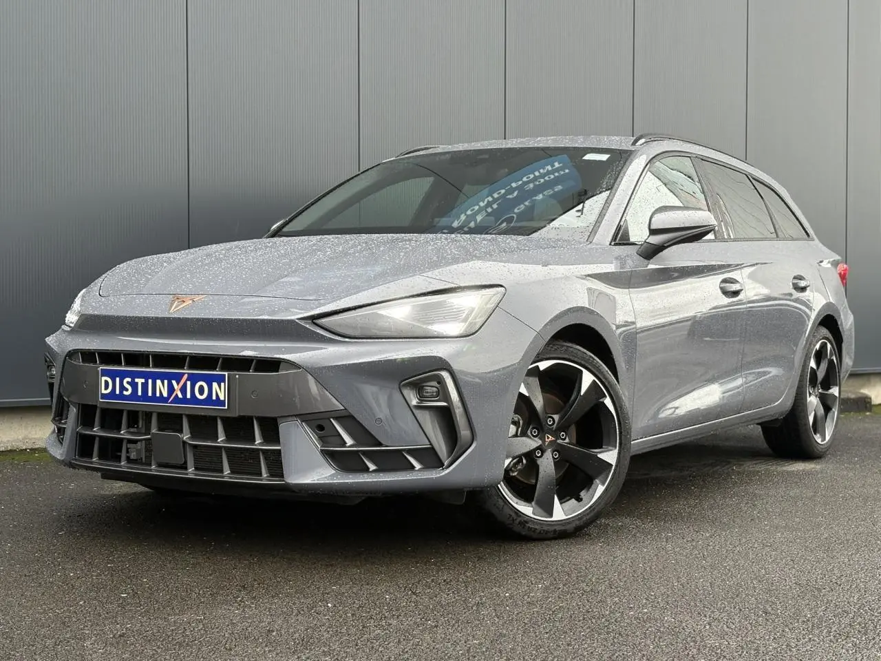 Vue 3/4 avant droite d'une CUPRA LEON ST 2025 gris Graphene avec jantes alliage noires et logo CUPRA sur calandre.