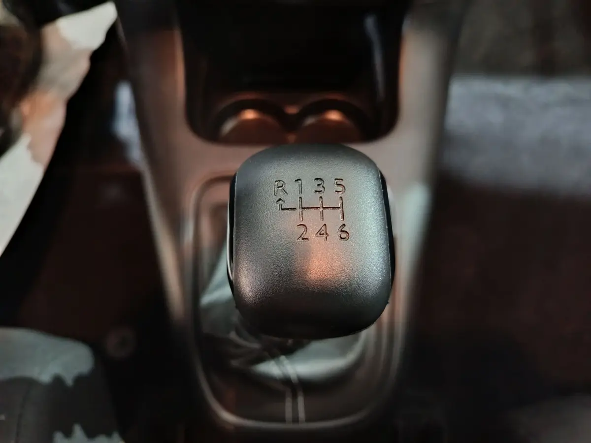 Gros plan sur le levier de vitesses manuel noir de la Citroën C3 2024 BlueHDi 100 BVM PLUS, intérieur sombre.