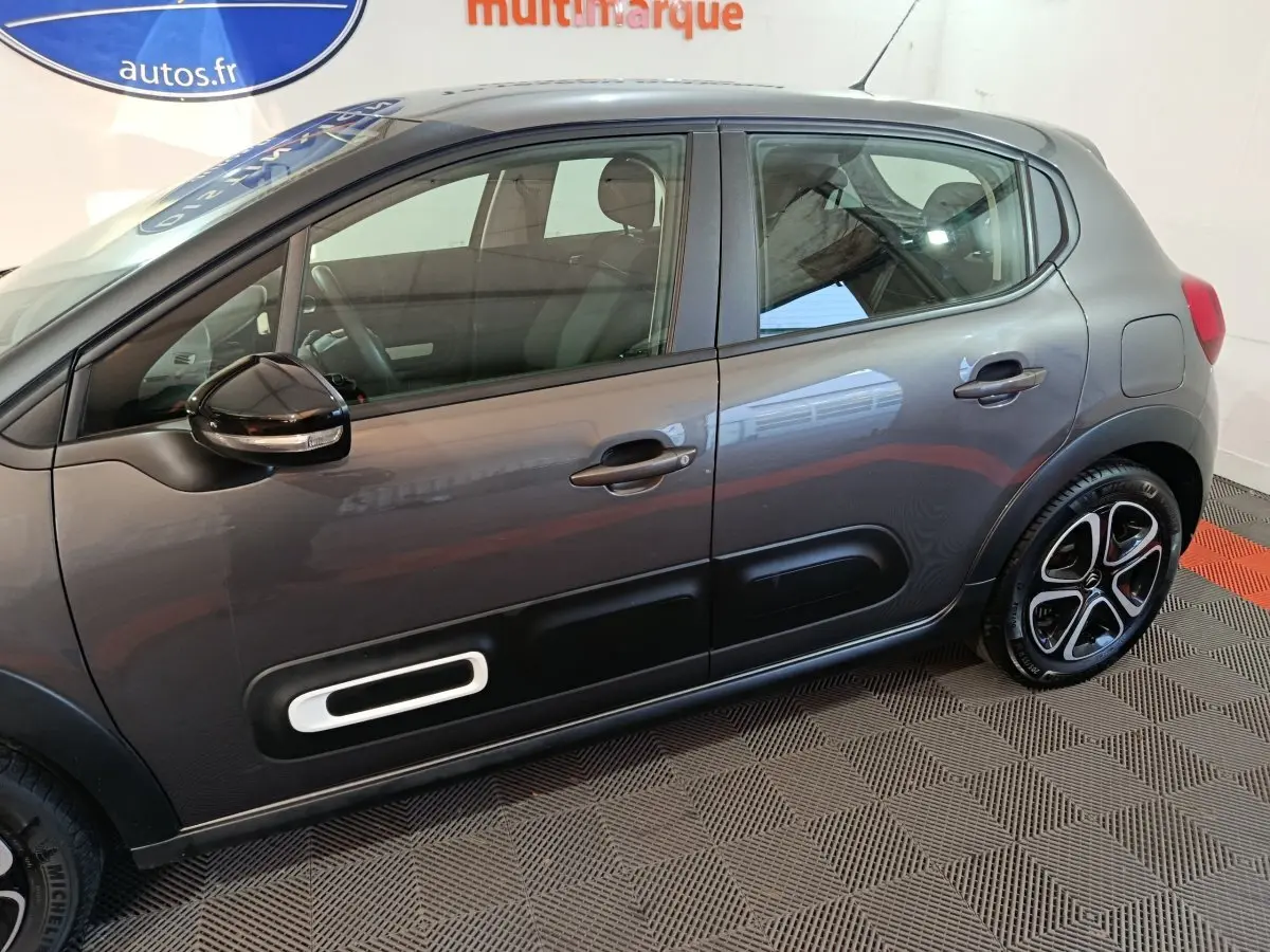 Vue de profil côté gauche d'une Citroën C3 2024 gris foncé avec protections latérales noires et jantes bicolores.