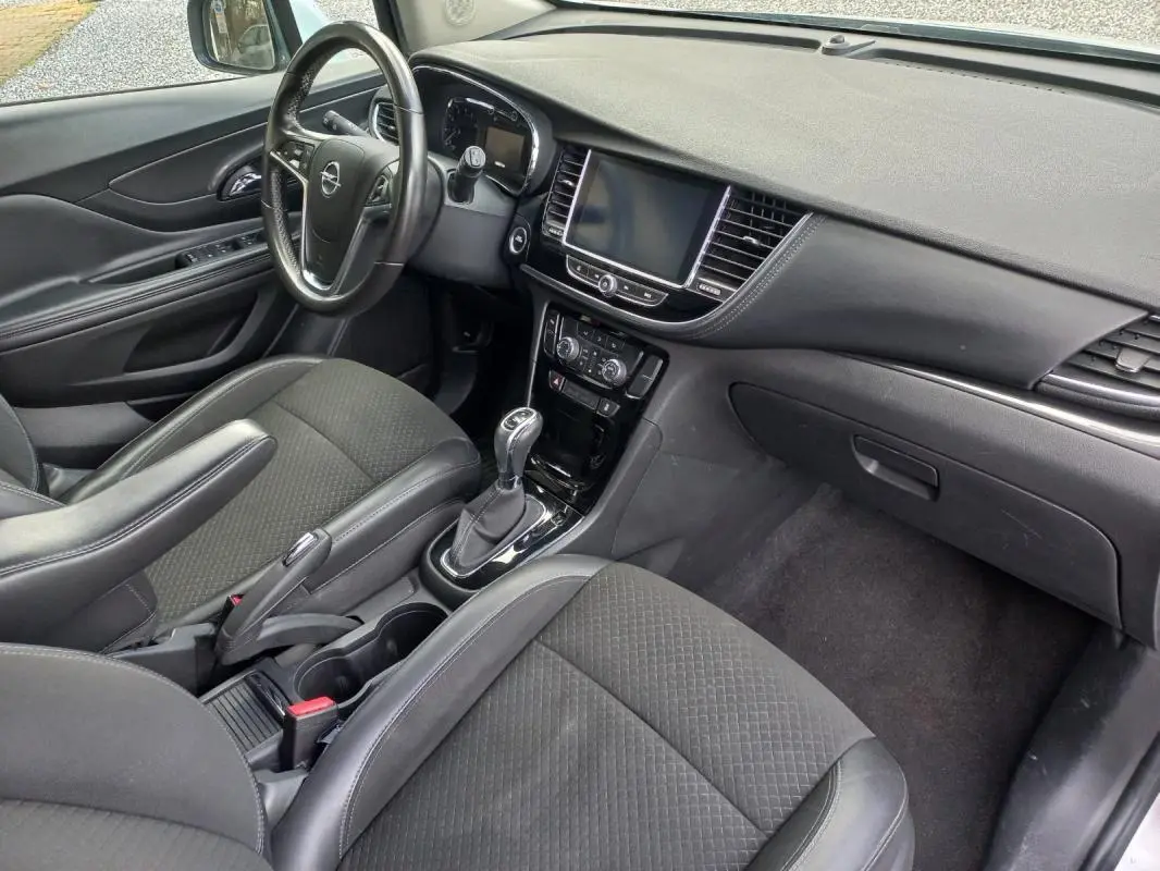 Vue intérieure côté conducteur de l’Opel Mokka X 2017, montrant tableau de bord noir et console centrale avec boîte automatique.