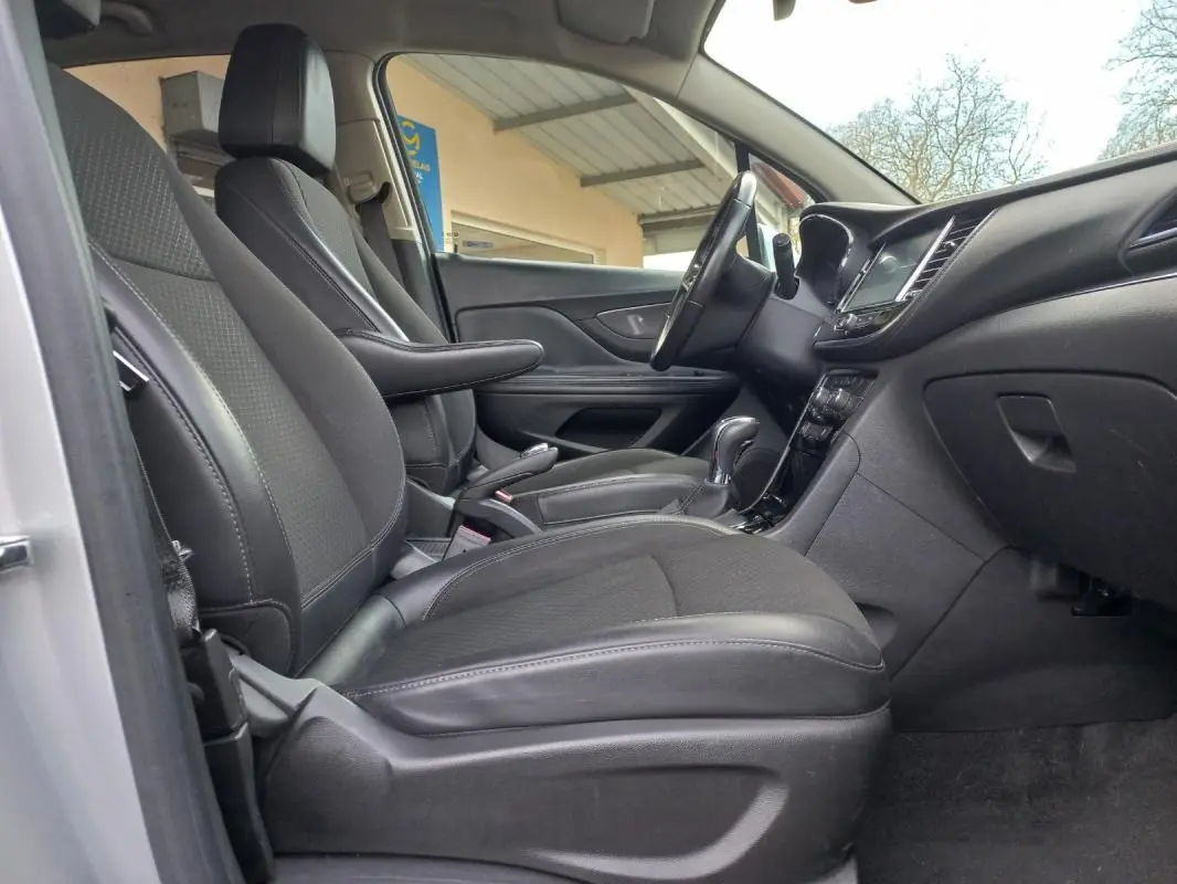 Vue intérieure côté conducteur de l’Opel Mokka X gris 2017, montrant sièges en cuir noir et tableau de bord moderne.