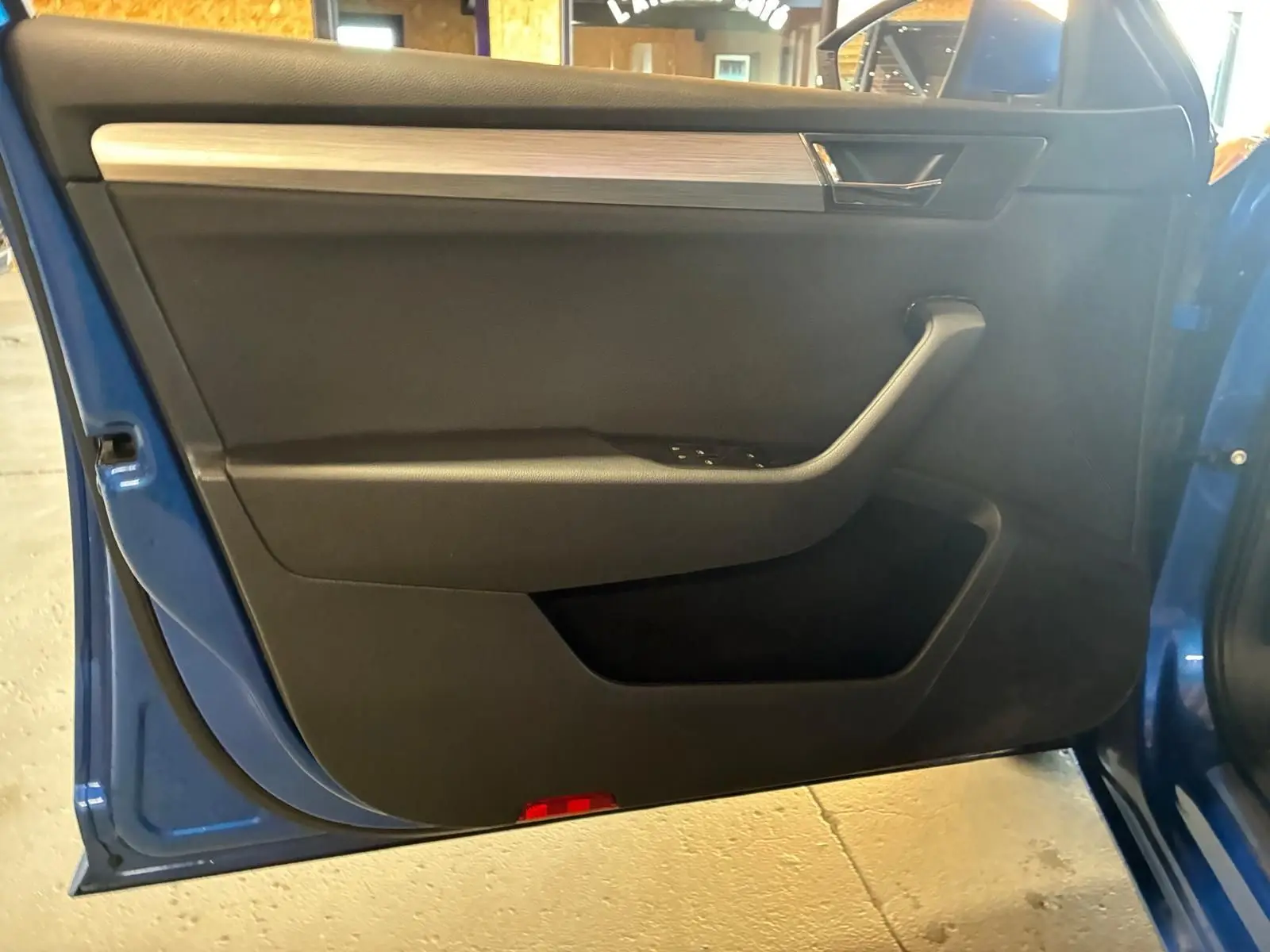 Intérieur de la porte avant gauche d'une Skoda Superb Combi bleu 2021, avec garniture noire et insert décoratif gris.