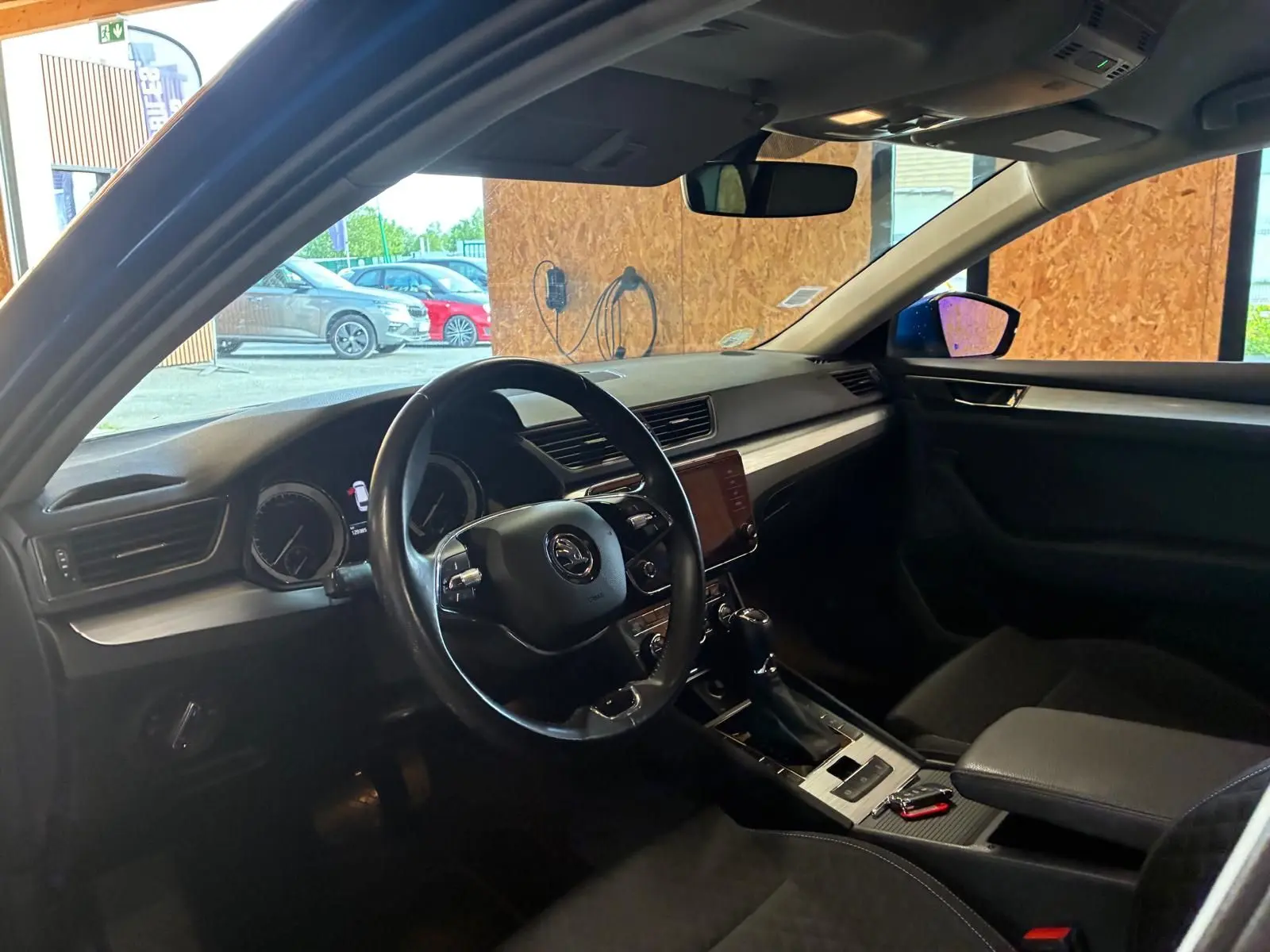 Vue intérieure côté conducteur du Skoda Superb Combi 2021, tableau de bord et volant noirs avec écran central tactile.