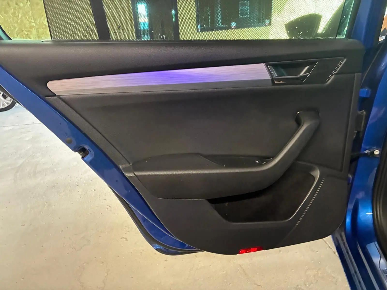 Vue rapprochée de la porte arrière gauche bleu métallisé d’une Skoda Superb Combi avec garniture intérieure noire et insert décoratif gris.