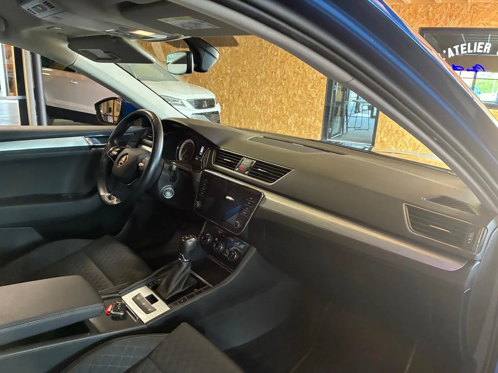 Vue intérieure côté conducteur du Skoda Superb Combi bleu 2021, avec tableau de bord moderne et volant multifonction.