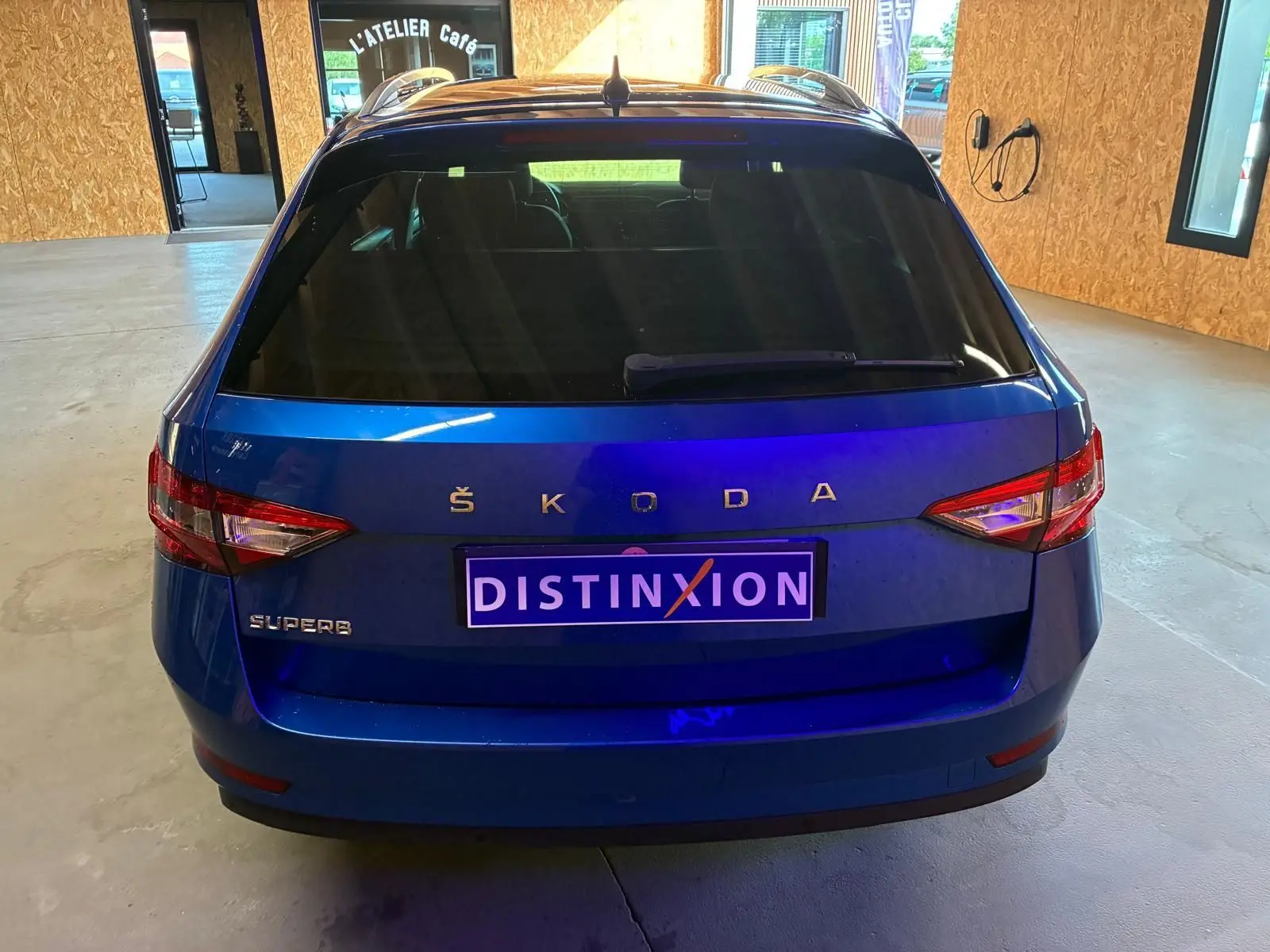 Vue arrière d'un Skoda Superb Combi bleu 2021 avec feux arrière allongés et plaque d'immatriculation Distinxion.