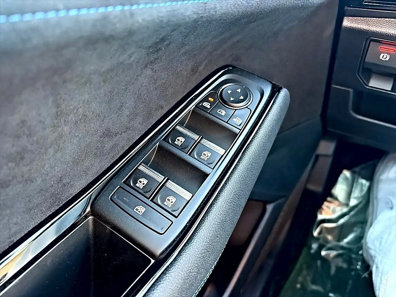 Gros plan sur la commande des vitres électriques côté conducteur du Renault Austral noir, avec revêtement noir et alcantara.