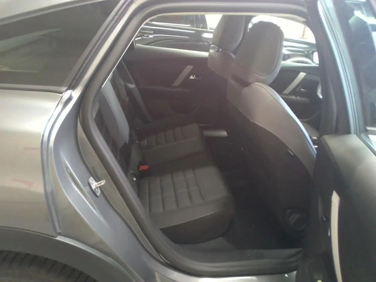 Vue intérieure côté arrière droit de la Citroën C4 hybride gris Mercury, montrant les sièges arrière en tissu noir.