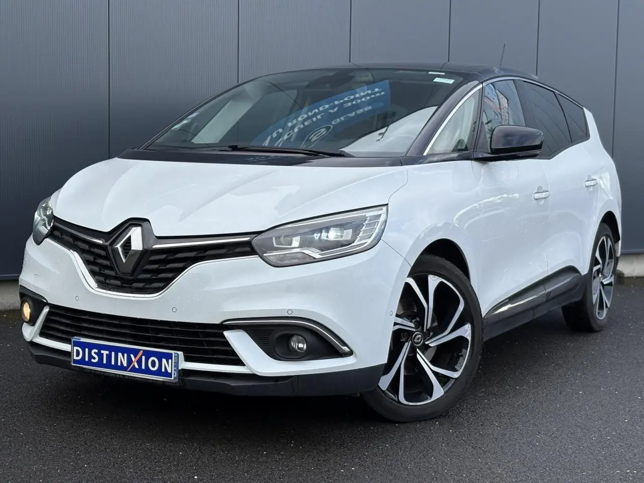 Renault Grand Scenic blanc nacré vu 3/4 avant droit avec toit noir étoilé et jantes alliage 20 pouces.