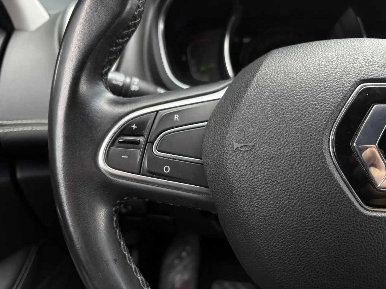 Gros plan sur le volant cuir noir du Renault Grand Scenic IV avec commandes intégrées sur le côté gauche.