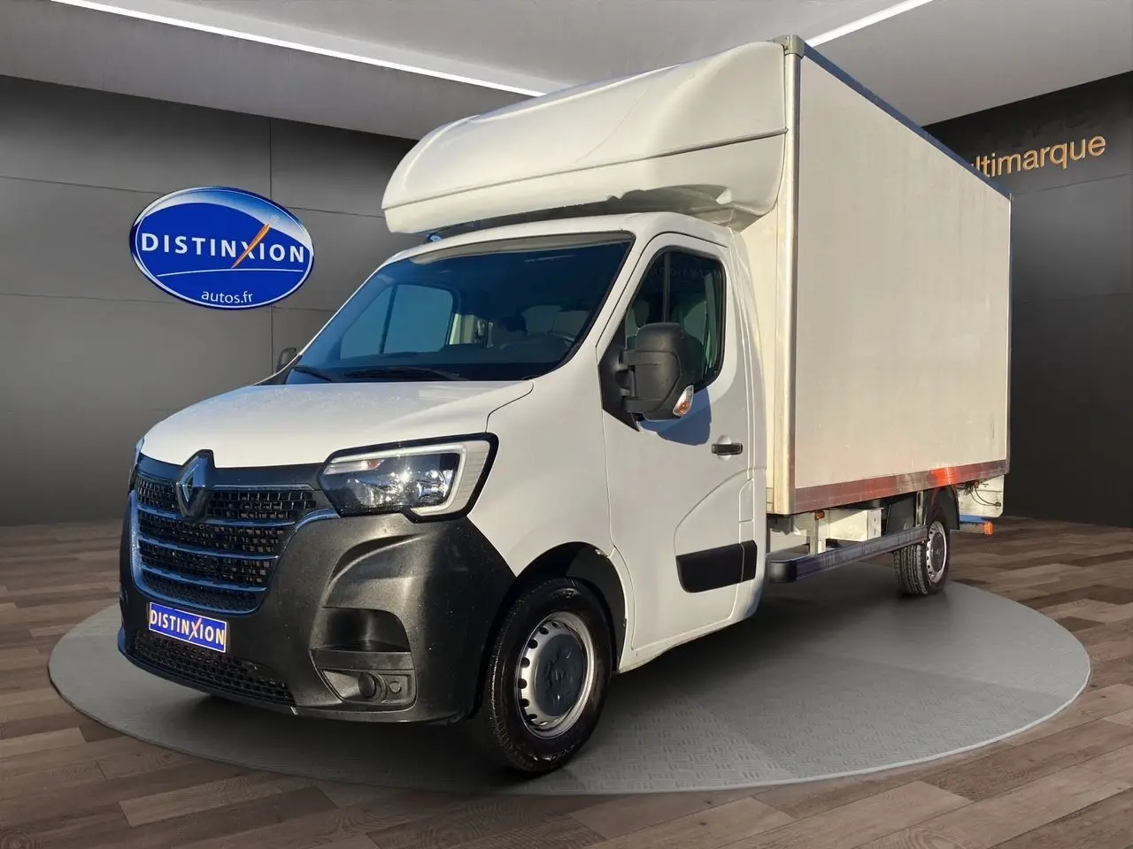 Renault Master blanc en 3/4 avant droit avec caisse hayon, calandre noire et jantes tôlées 16 pouces visibles.