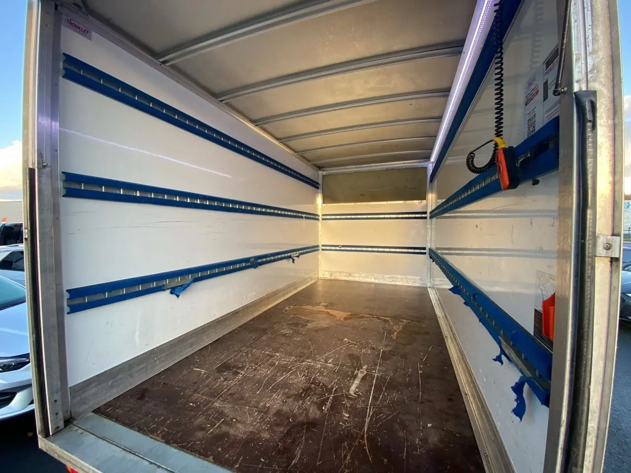 Intérieur du coffre blanc du Renault Master Châssis Cabine 2023 vu de l'arrière, avec rails de fixation bleus et plancher usé.