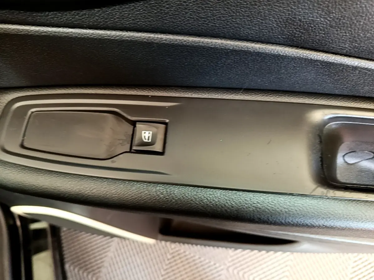 Gros plan sur le bouton de commande de la vitre électrique côté conducteur du Renault Captur Business noir de 2018.