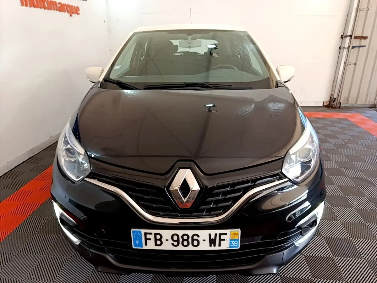 Vue avant d'un Renault Captur Business TCe 90 noir avec feux de jour LED allumés dans un showroom.