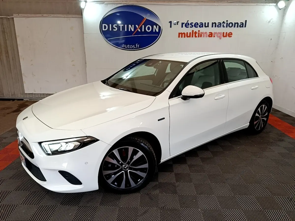 Vue 3/4 avant droite d'une Mercedes Classe A Berline blanche avec jantes noires et phares LED allumés.