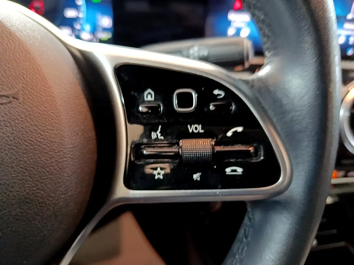 Gros plan sur le volant cuir multifonctions côté gauche de la Mercedes Classe A Berline blanche de 2020.