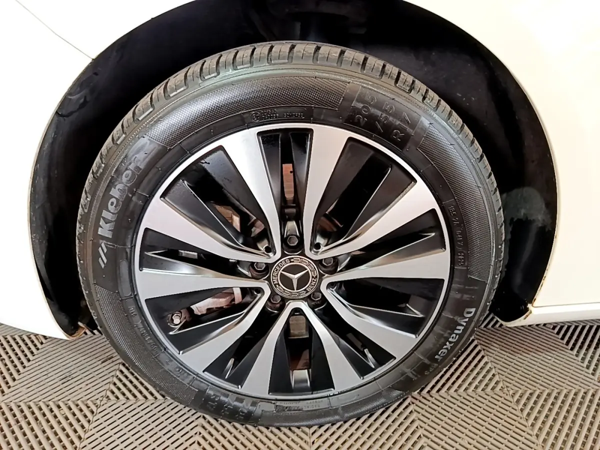 Gros plan sur la roue avant droite d’une Mercedes Classe A blanche avec jante alliage bicolore et logo central.