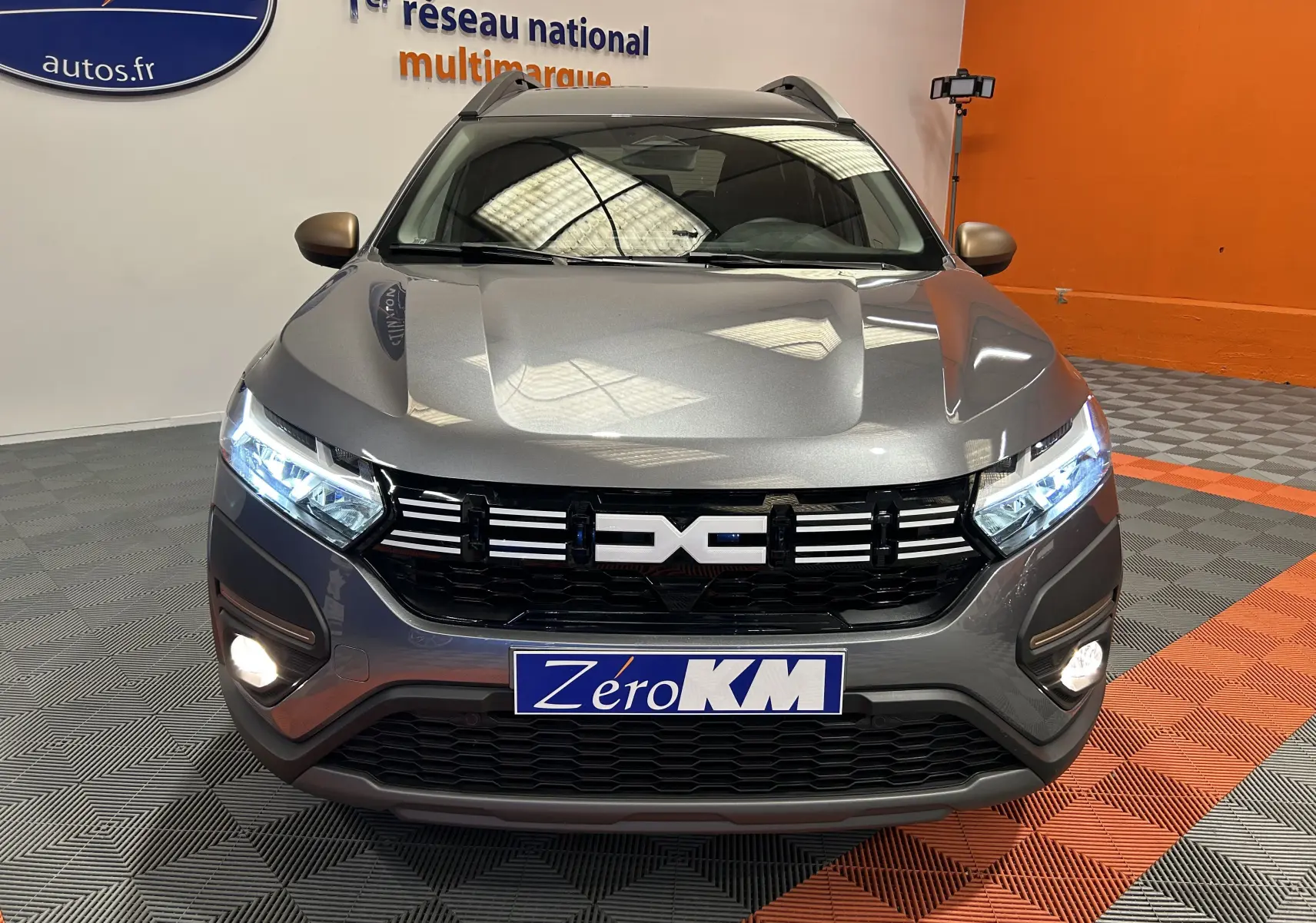Vue de face du Dacia Jogger gris schiste métal avec phares LED allumés et calandre noire distinctive.
