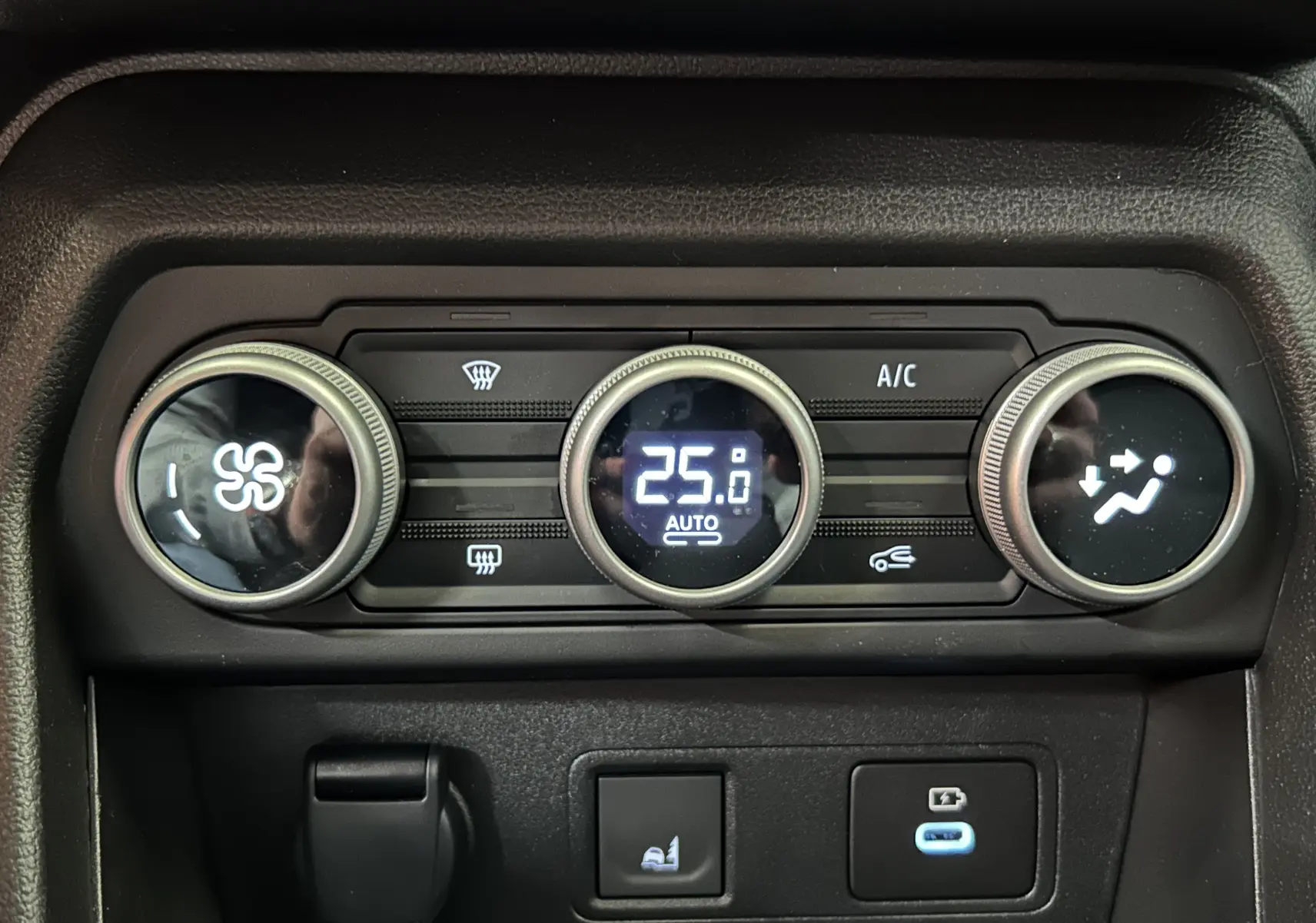 Gros plan sur la commande de climatisation digitale du Dacia Jogger gris schiste, affichant 25°C en mode automatique.