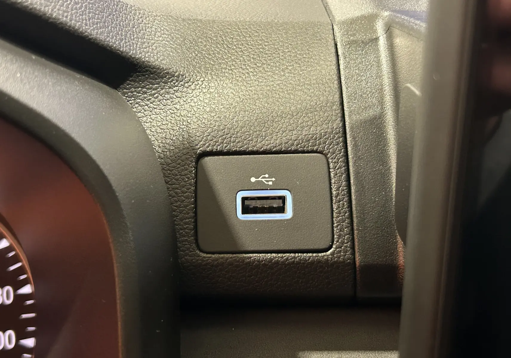 Gros plan sur la prise USB encadrée de bleu sur le tableau de bord noir du Dacia Jogger Gris Schiste Métal.