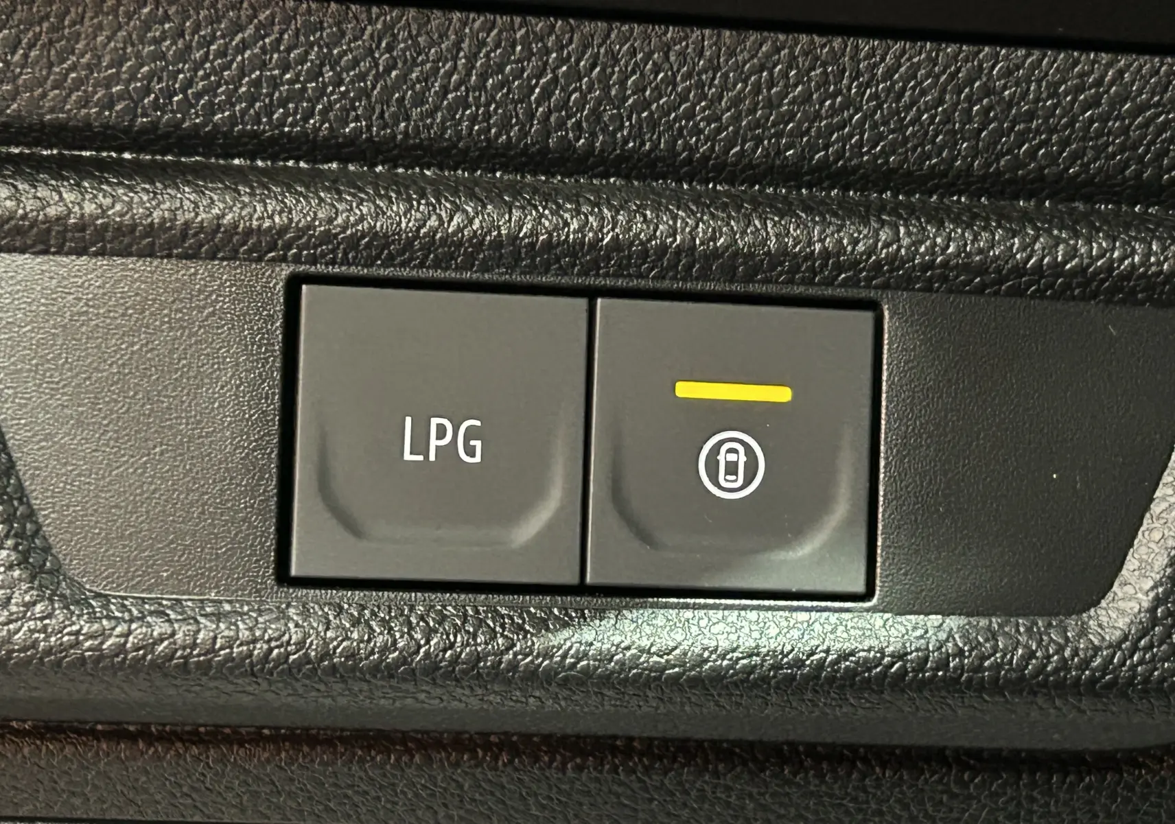 Gros plan sur les boutons de commande LPG et verrouillage centralisé dans l’habitacle noir du Dacia Jogger gris Schiste Metal.