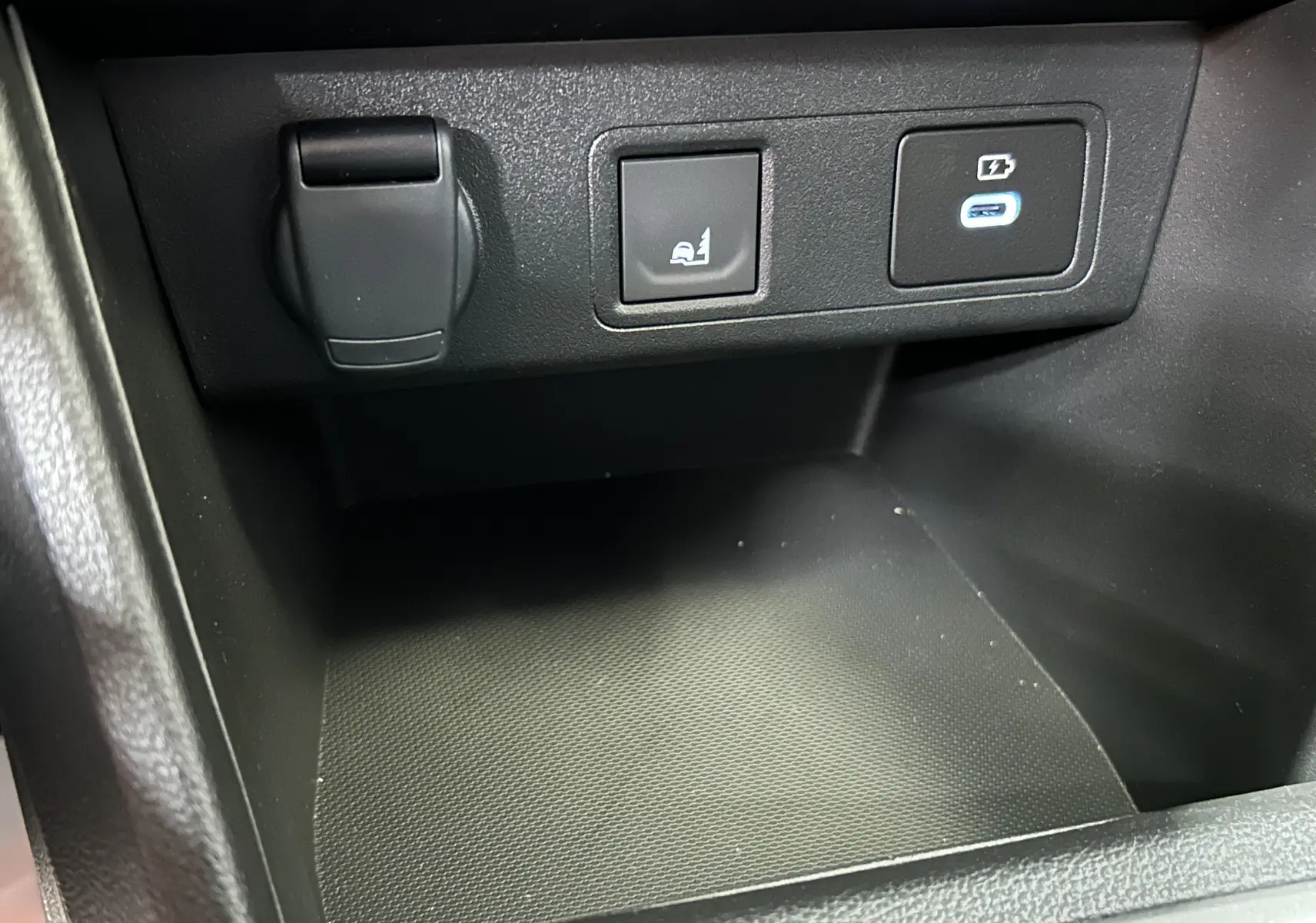 Détail intérieur du compartiment central avec prise 12V, bouton de fonction et port USB-C éclairé sur Dacia Jogger 2026.