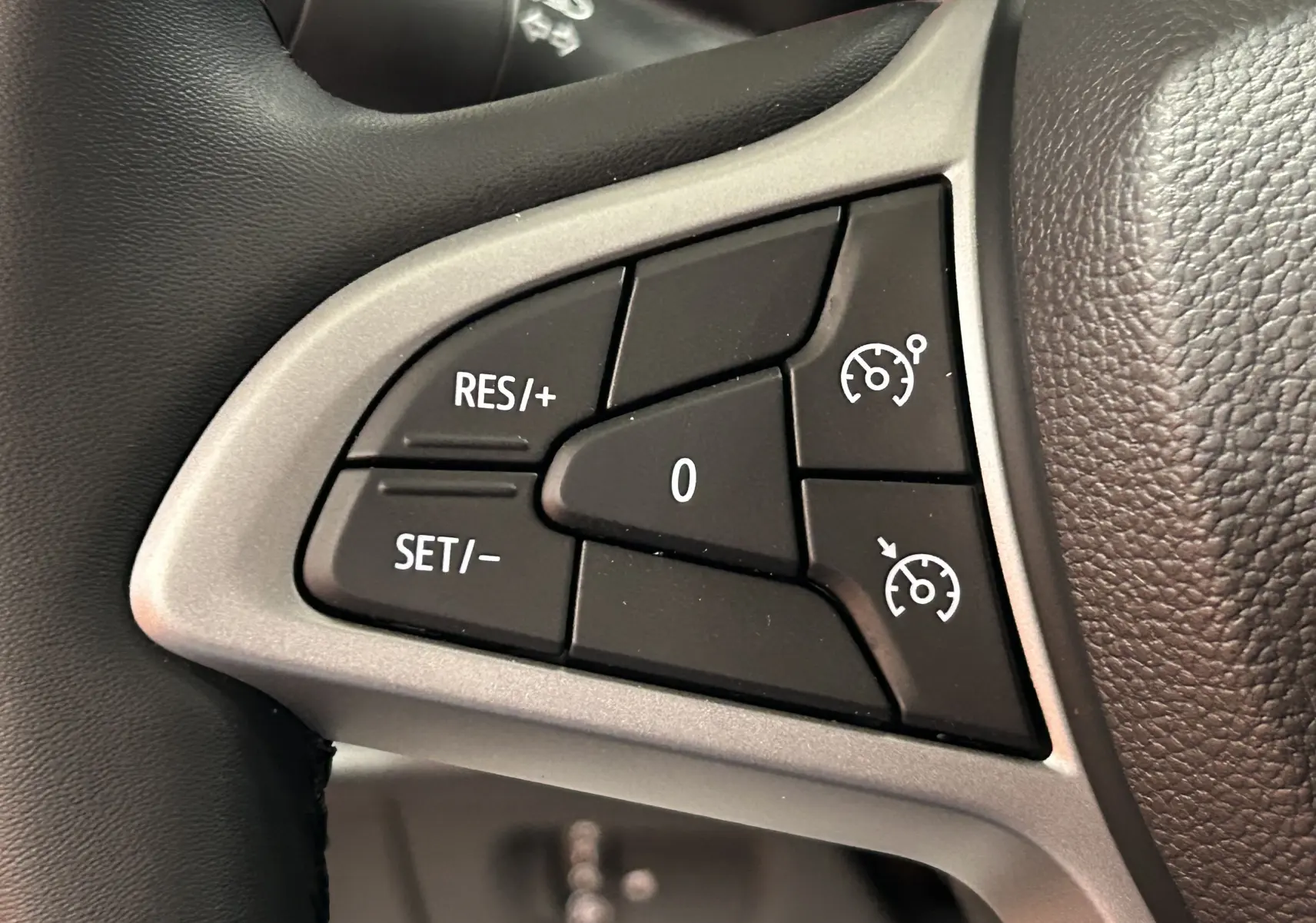 Gros plan sur les commandes de régulateur de vitesse au volant d’un Dacia Jogger gris schiste métal.