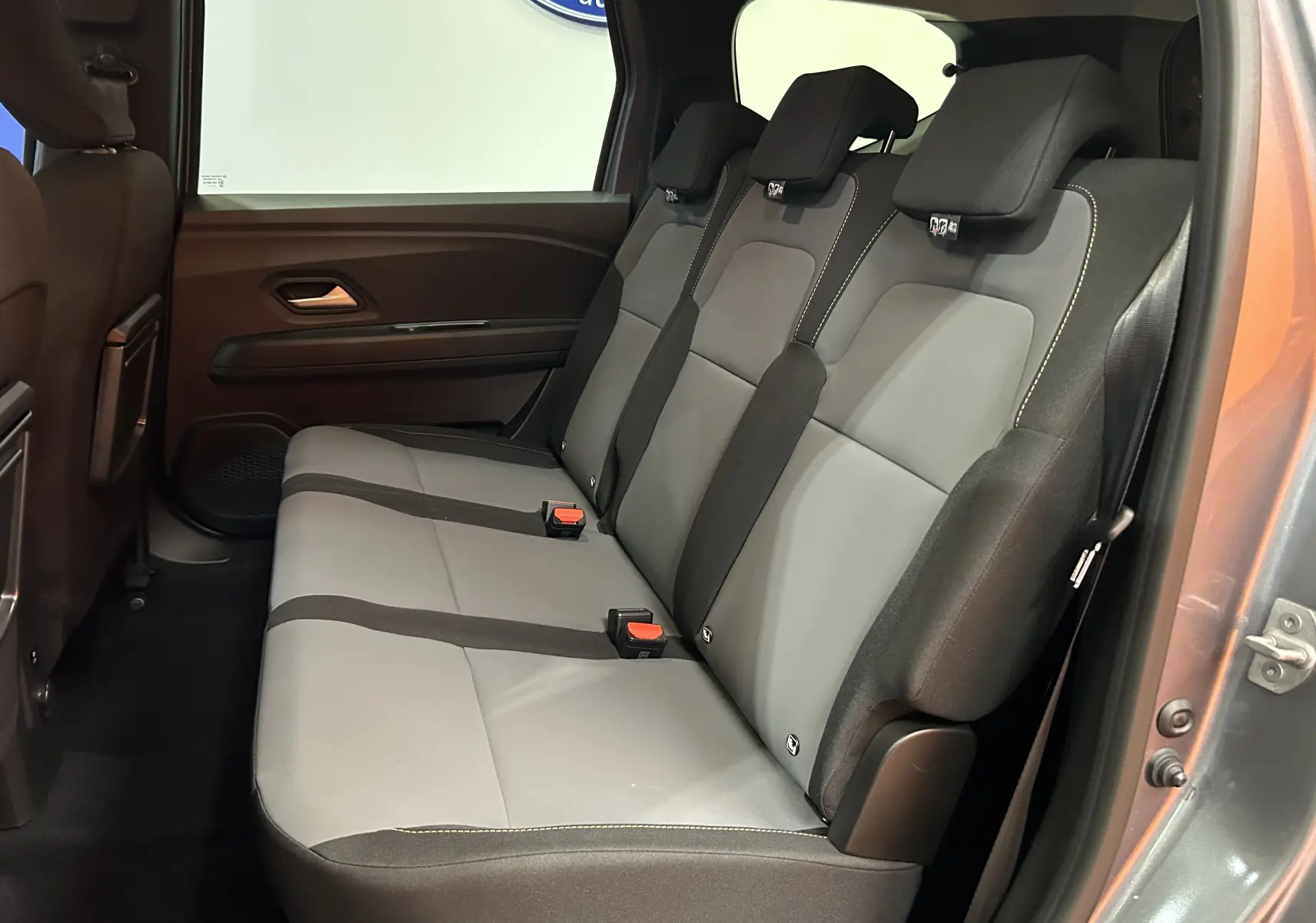 Vue latérale droite sur la banquette arrière grise et noire du Dacia Jogger 2026, avec ouverture de porte visible.