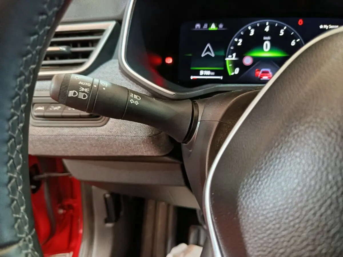Vue rapprochée du combiné d'instruments numérique et du commodo d'éclairage dans l'habitacle d'une Renault Clio rouge 2024.