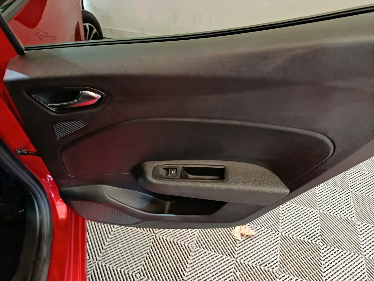 Vue intérieure de la porte arrière gauche rouge d'une Renault Clio 2024, avec poignée et commande de vitre noire.