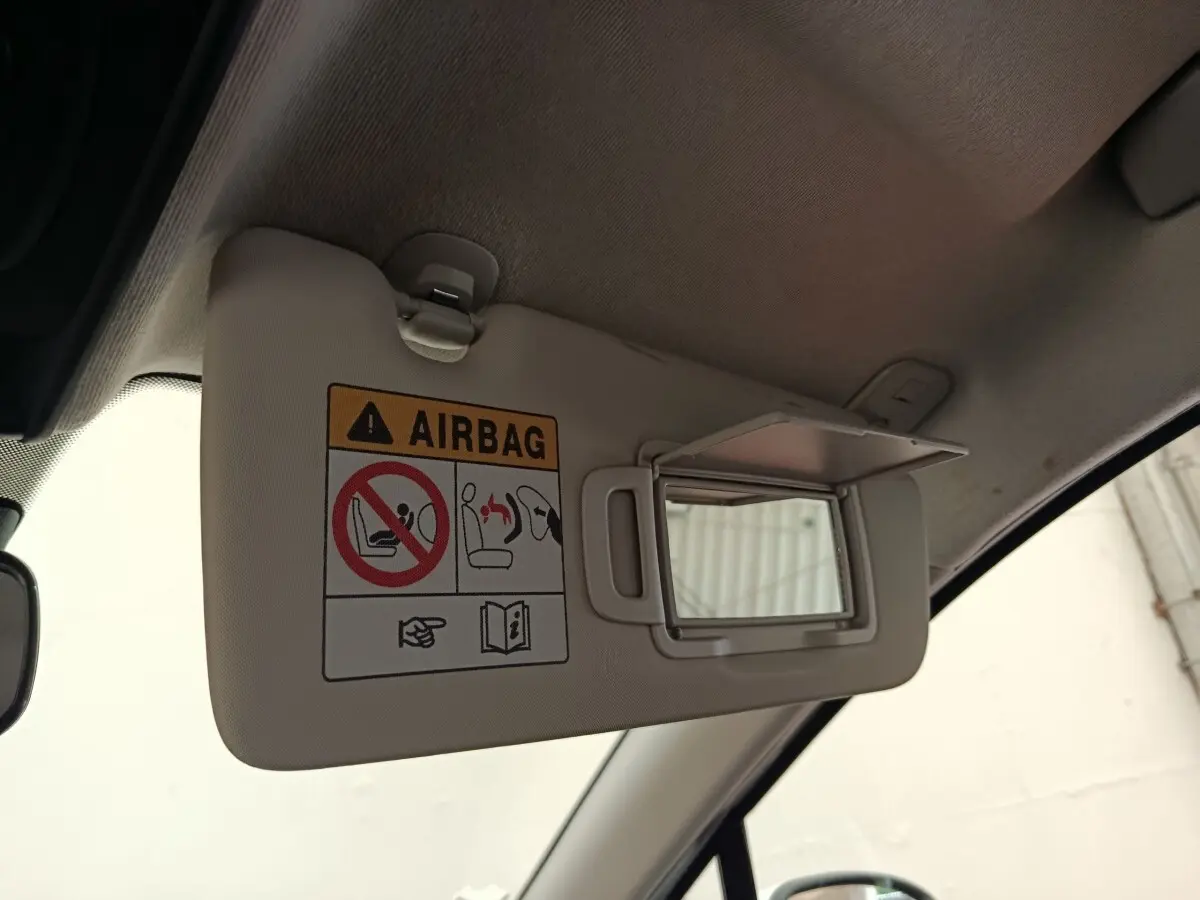 Pare-soleil intérieur beige avec miroir de courtoisie ouvert dans une Renault Clio blanche, vue côté conducteur.