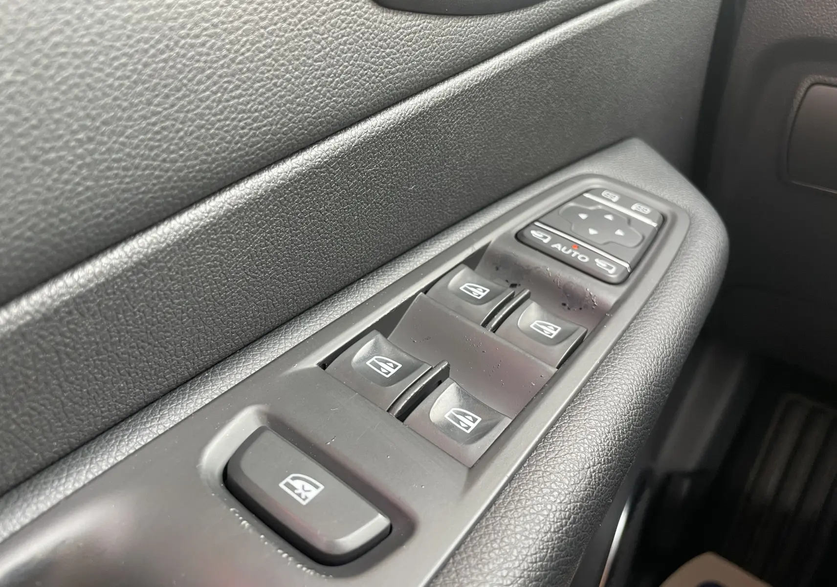 Gros plan sur les commandes des vitres électriques côté conducteur d'un Renault Captur noir étoile toit ivoire 2017.