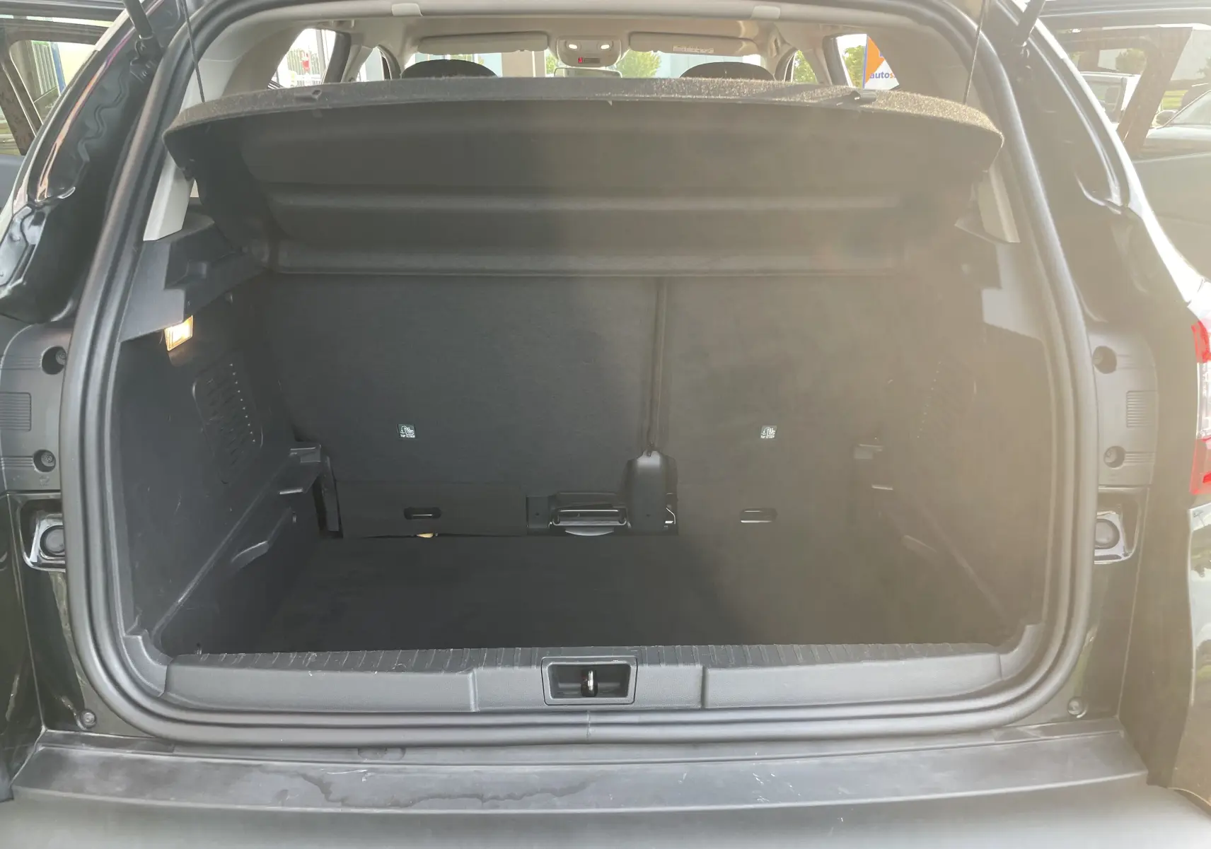 Coffre ouvert vu de l'arrière d'un Renault Captur noir étoile, montrant un espace de chargement propre et spacieux.