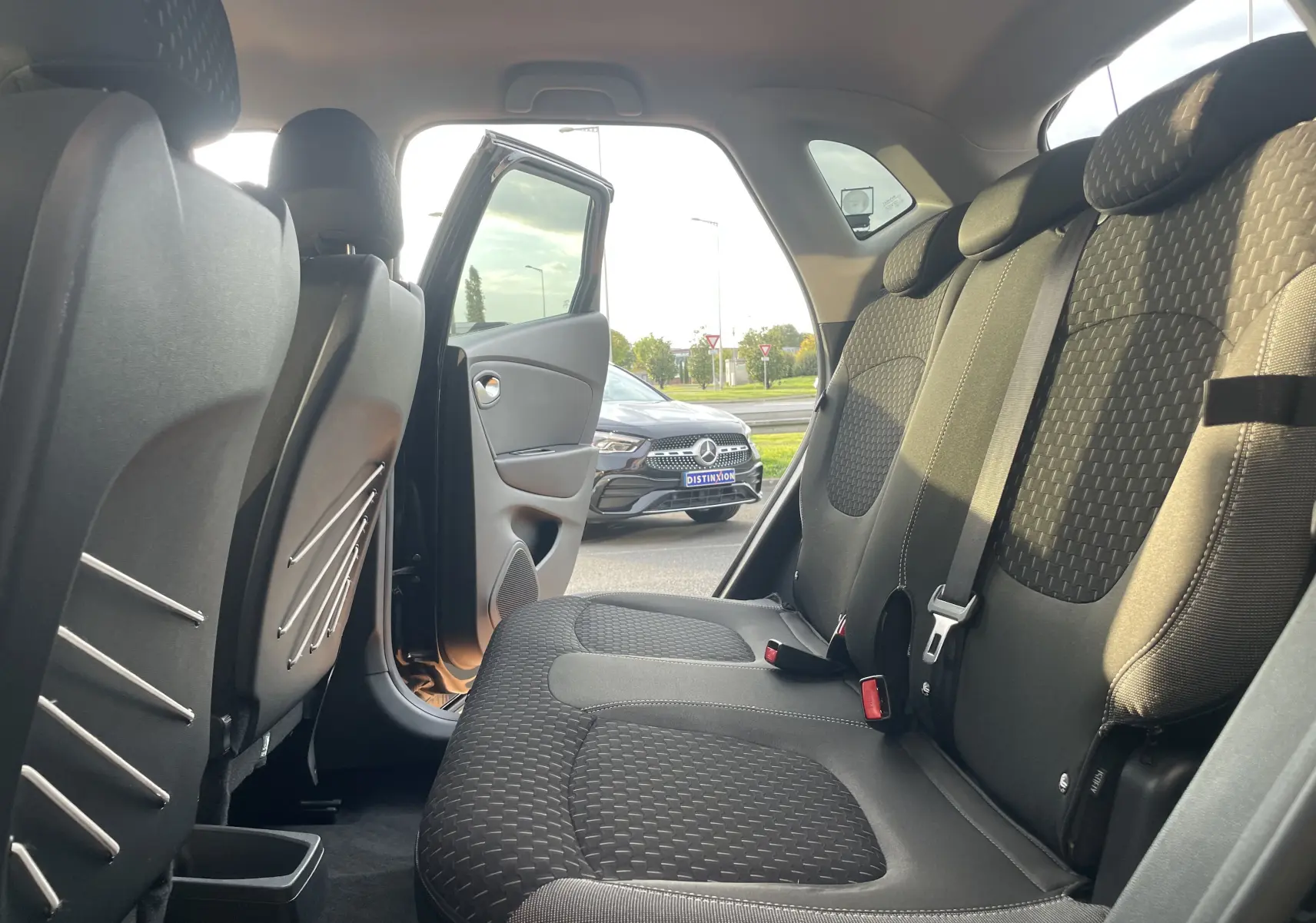 Vue intérieure arrière droite du Renault Captur noir étoile avec sièges tissu gris beige et porte arrière ouverte.