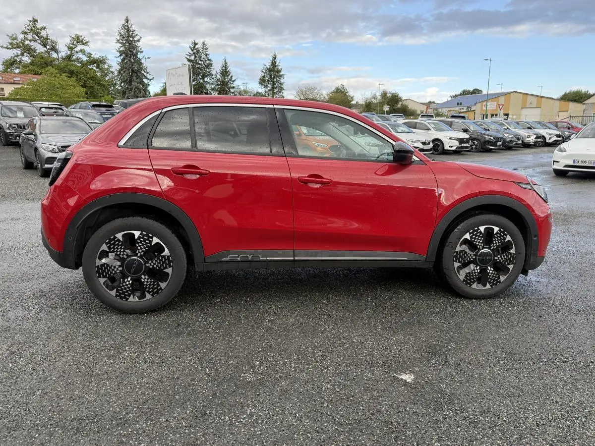 Vue latérale gauche d'une FIAT 600 1.2 Hybrid rouge avec jantes alliage noires et logo 600 sur la porte.