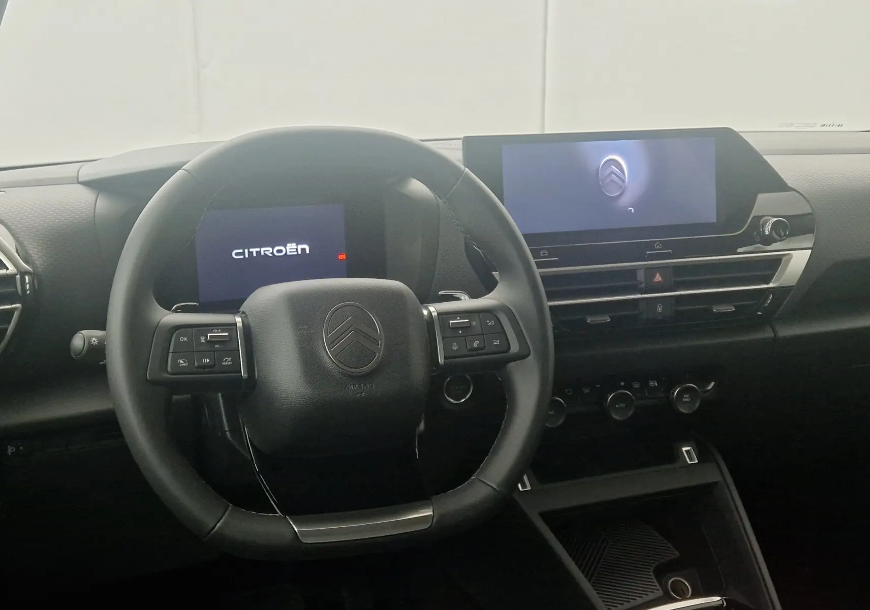 Vue intérieure du tableau de bord et volant noir du Citroën C4 1.2 Hybrid 136 Business Edition avec écran tactile central allumé.