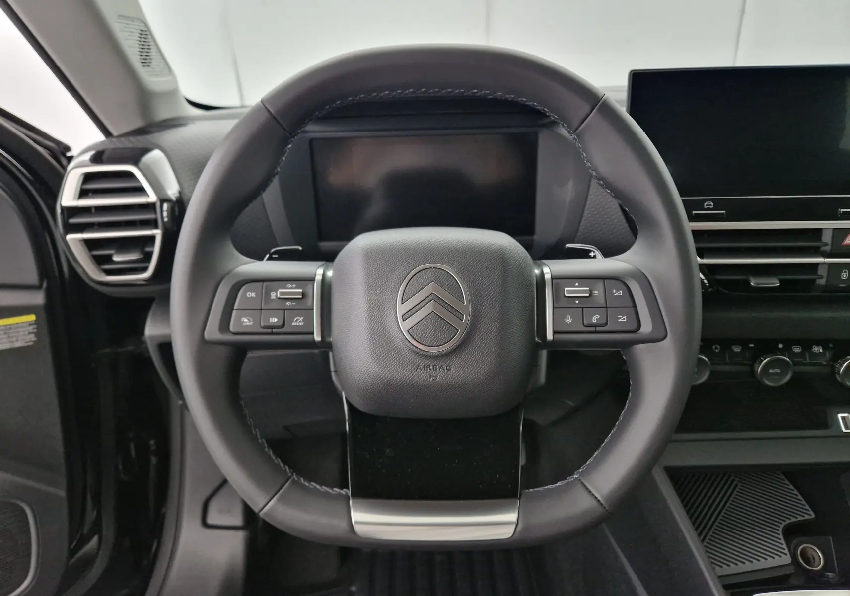 Vue frontale du volant cuir noir de la Citroën C4 1.2 Hybrid 136 Business Edition avec commandes intégrées et tableau de bord digital.