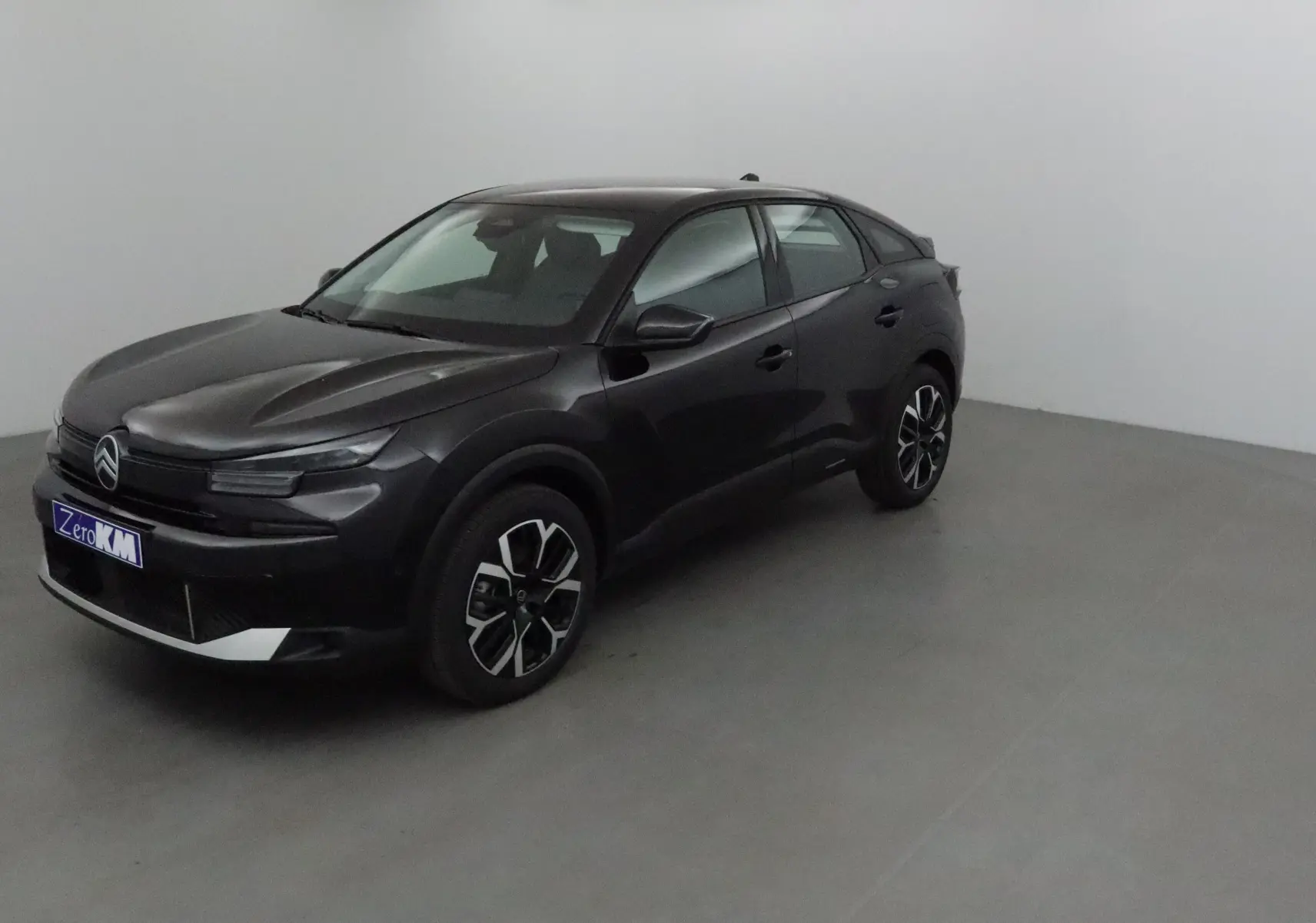 Citroën C4 noire vue en 3/4 avant droit dans un espace intérieur neutre, avec jantes noires et argentées.