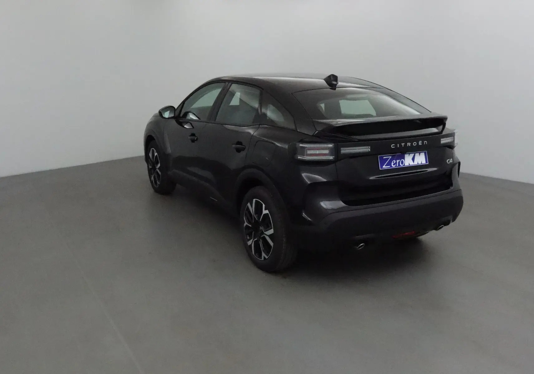 Citroën C4 noir vue 3/4 arrière droit en intérieur, avec jantes noires et feux arrière LED distinctifs.