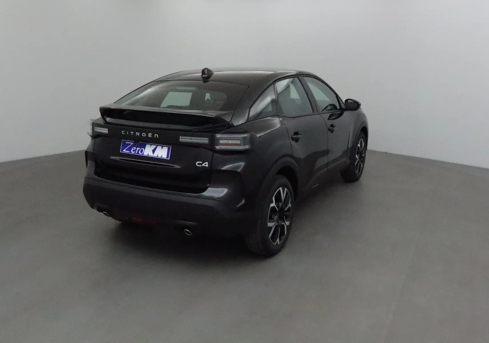 Citroën C4 noire vue 3/4 arrière droit dans un studio, avec feux arrière LED et jantes alliage noires.