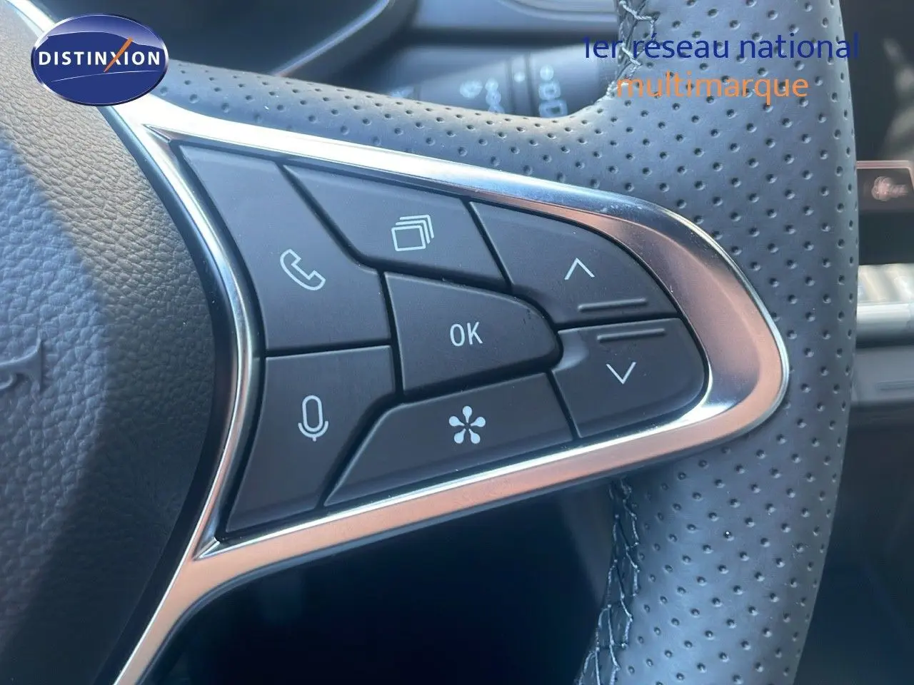 Gros plan sur les commandes du volant en cuir perforé du Renault Captur E-Tech hybride noir étoile métal 2025.