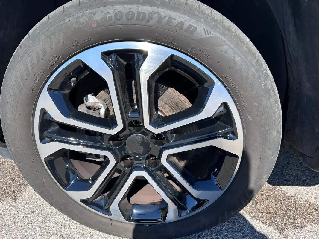 Gros plan sur la jante alliage 18 pouces bicolore noir et argent du Jeep Compass gris 2024.