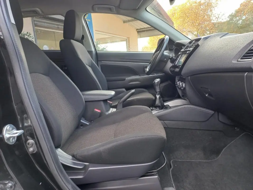 Intérieur avant côté gauche du Mitsubishi ASX noir 2020, montrant sièges, accoudoir central et tableau de bord.