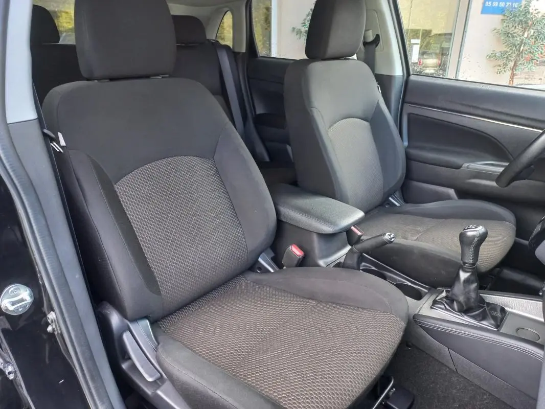 Vue intérieure côté gauche du Mitsubishi ASX noir 2020, montrant les sièges avant et l'accoudoir central.