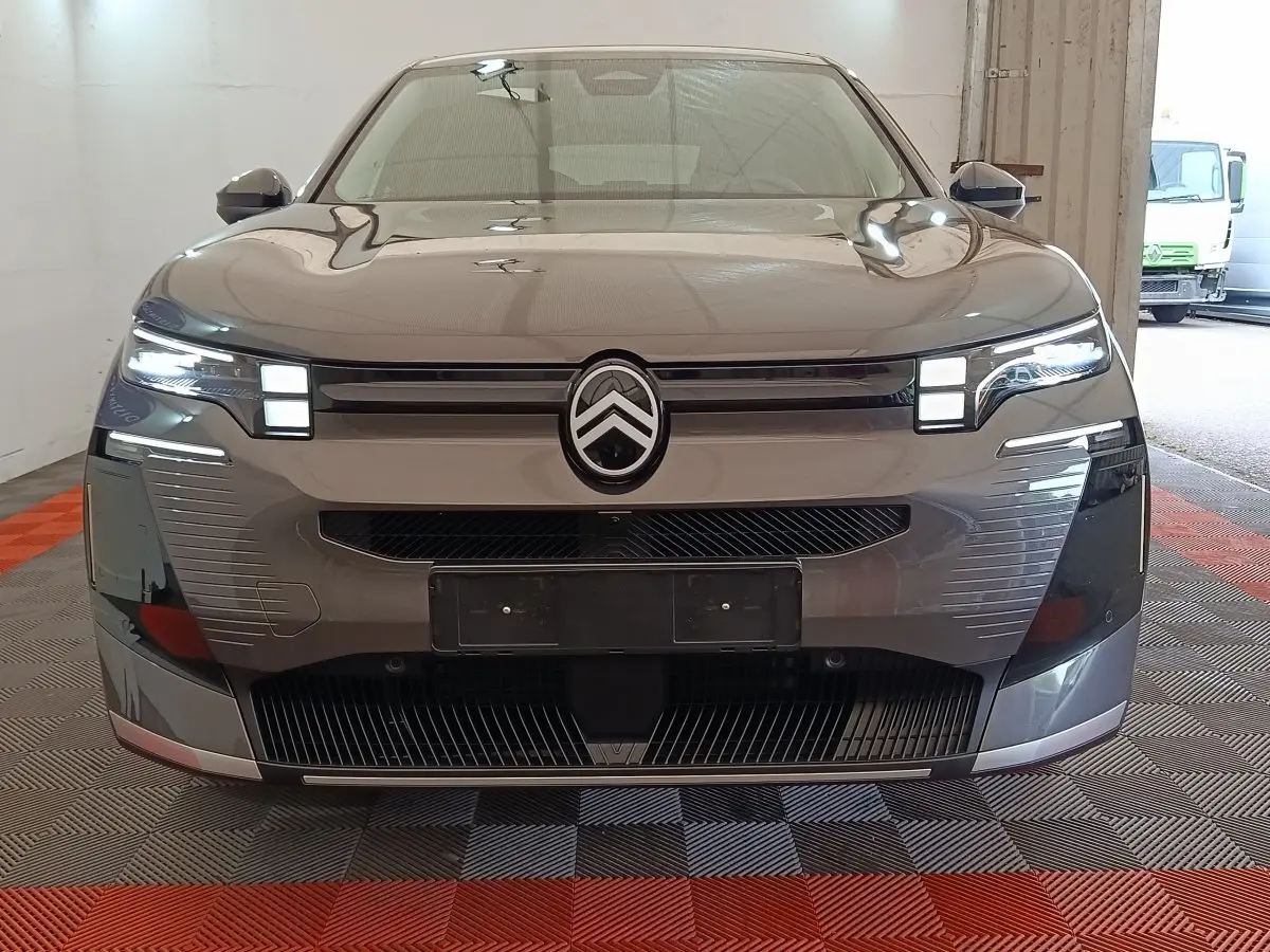 Vue frontale d'une Citroën C5 Hybride gris foncé avec phares LED et calandre distinctive en intérieur.