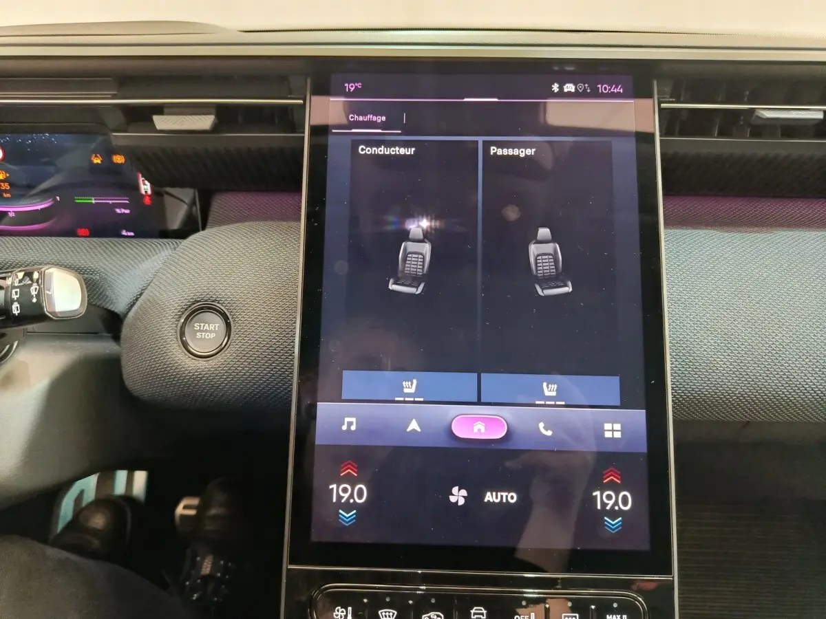 Vue rapprochée du tableau de bord central tactile de la Citroën C5 hybride gris foncé, affichant le réglage du chauffage des sièges.