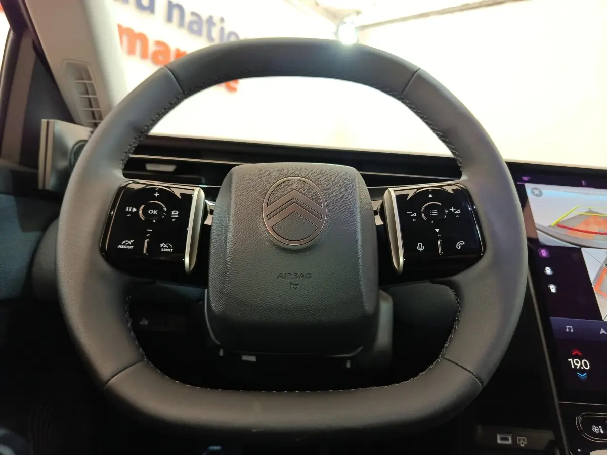 Volant cuir noir de Citroën C5 Hybride 2026, vue frontale avec commandes multifonctions et écran tactile partiel à droite.