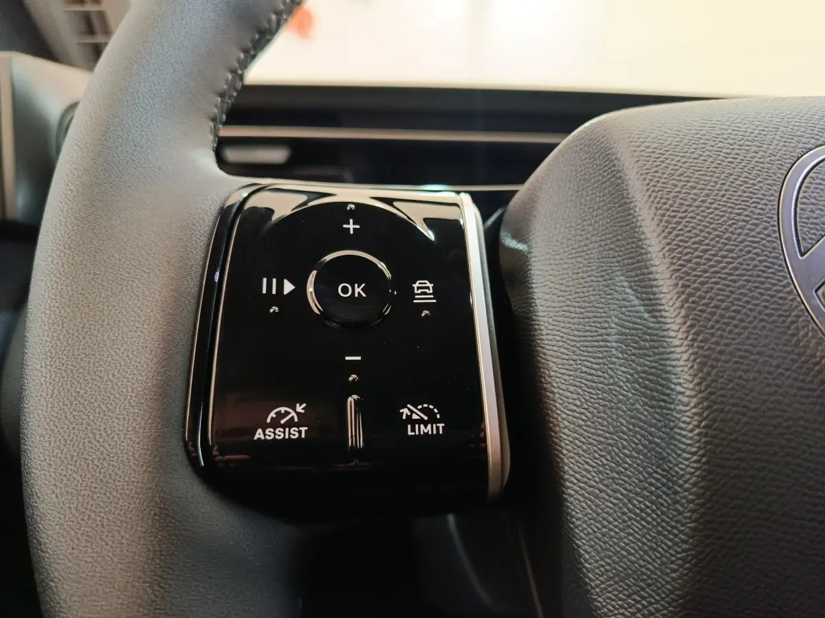 Gros plan sur les commandes noires du volant cuir du Citroën C5 Hybride 2026, côté gauche.